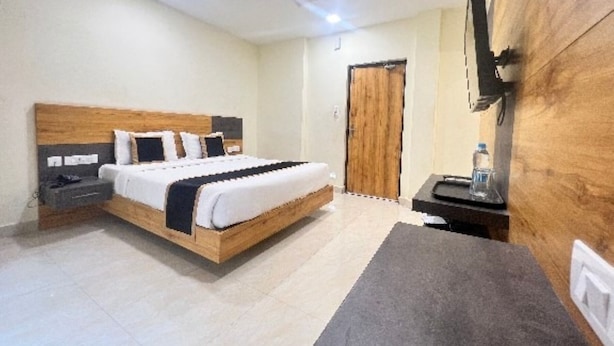 Une chambre à coucher avec un lit en bois, une table de chevet, un bureau avec une chaise, une télévision et une armoire en bois.