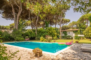 Ein von Bäumen umgebener Pool und ein Haus.