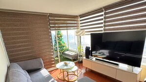 A modern living room with a grey sectional sofa, a flat-screen TV on a white console, and a glass coffee table. - South Beach Front Apartment (Antofagasta)