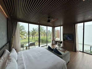 A modern hotel room with a large bed, a dining area, and a TV. - Wyndham Hoi An Royal Beachfront Resort (Hoi An)