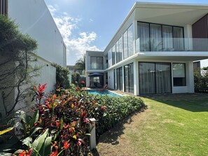 A modern two-story house with a swimming pool, surrounded by well-maintained lawns and tropical plants. - Wyndham Hoi An Royal Beachfront Resort (Hoi An)