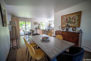 A dining area with a wooden table, yellow chairs, a bowl of fruit, and a painting on the wall. - La Villa Coucou (Nîmes)