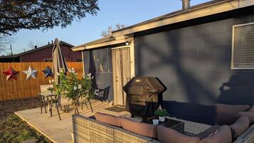 Een achtertuin met een overdekte barbecue, zitplaatsen buiten en een houten omheining.