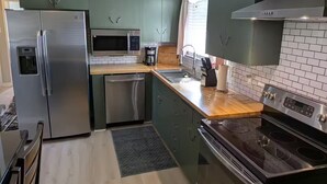 Cocina moderna con electrodomésticos de acero inoxidable, microondas y lavavajillas.