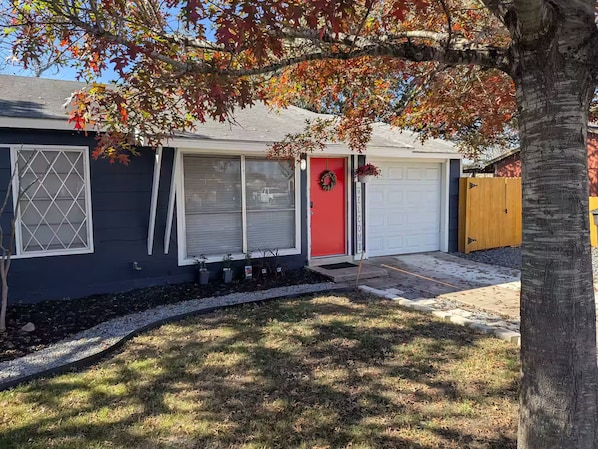 A residential house with a red door, a garage, and a tree in the foreground. - Patriot's Post - just renovated near Lackland AFB (San Antonio)