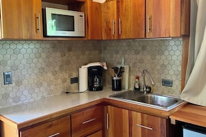 A kitchen with wooden cabinets, a microwave, a coffee maker, and a sink. - Monkey House (Mirador)