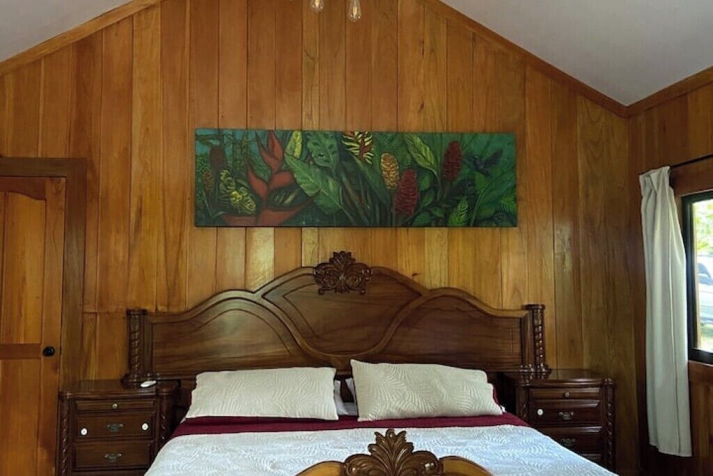 A wooden-paneled room with a large bed, two nightstands, and a wall mural.