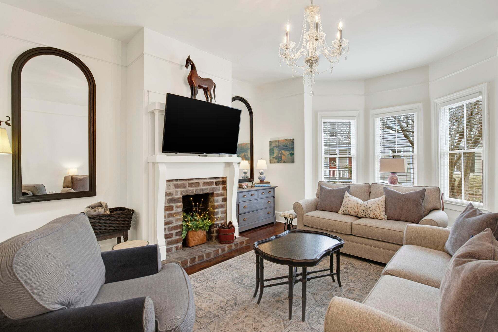 A living room with a fireplace, sofa, television, and chandelier.