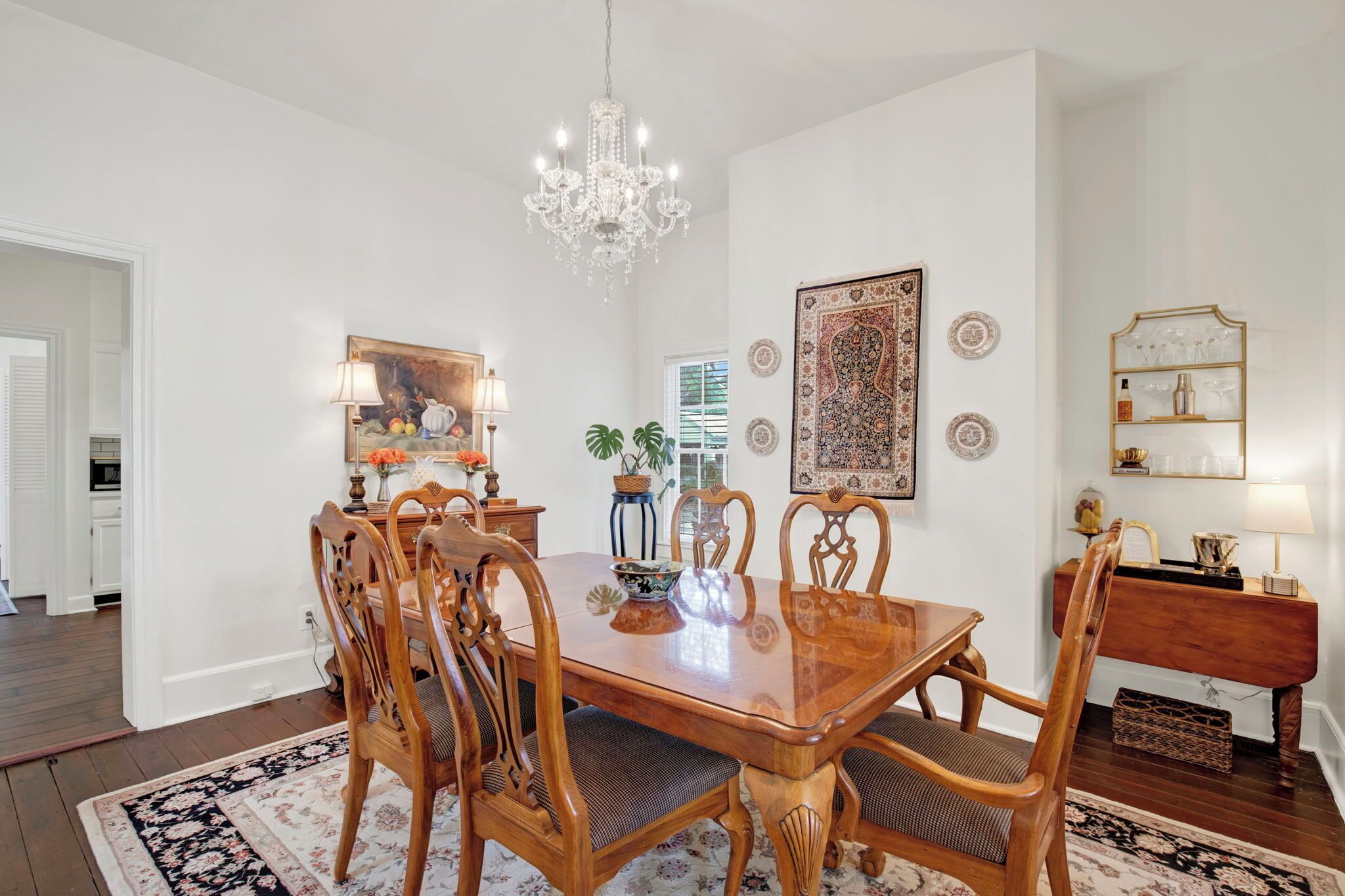 A dining area with a wooden table and chairs, a chandelier, and decorative plates on the walls.