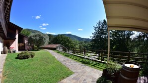 A stone pathway leading to a building with a wooden fence and a view of mountains. - Tenuta Valdomini (Attimis)