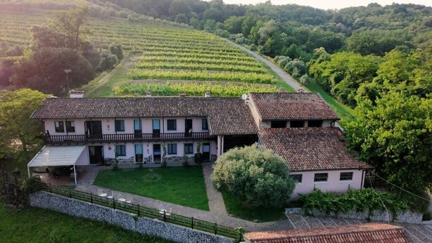 A large, two-story house with a tiled roof, surrounded by lush greenery and vineyards. - Tenuta Valdomini (Attimis)