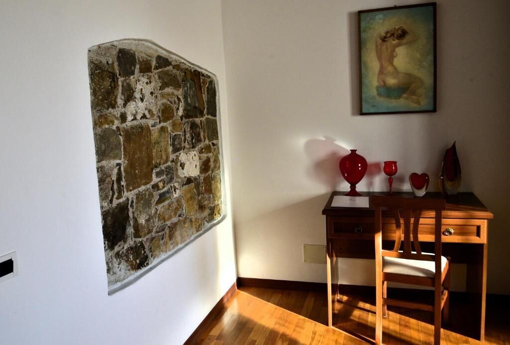Una habitación con pared de piedra, un escritorio de madera y una silla.