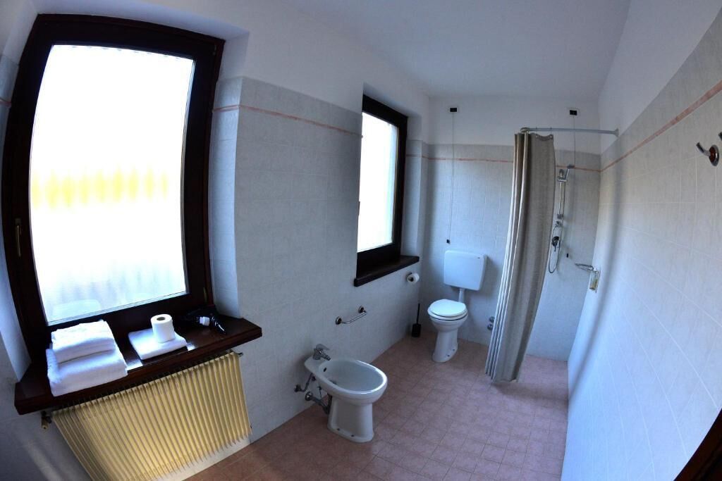 Baño pequeño con ventana, inodoro, bidé y ducha.