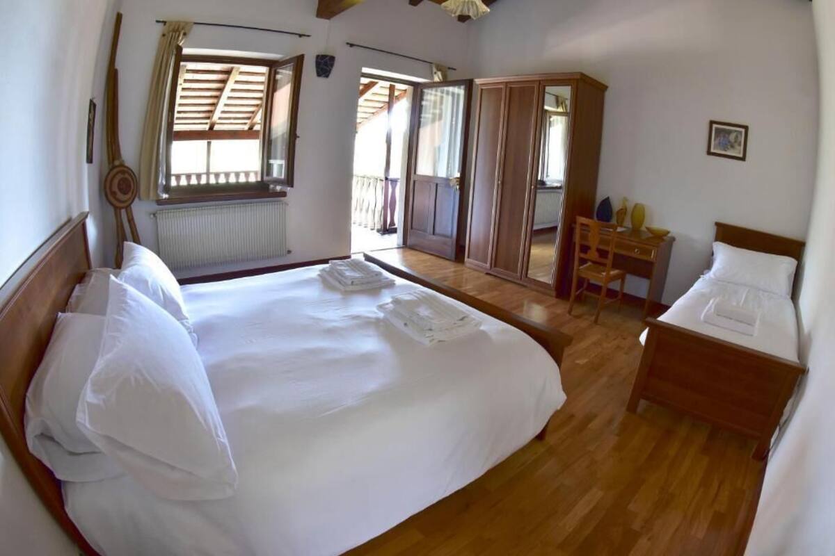 A bedroom with a large bed, wooden floor, a desk, and a wardrobe.