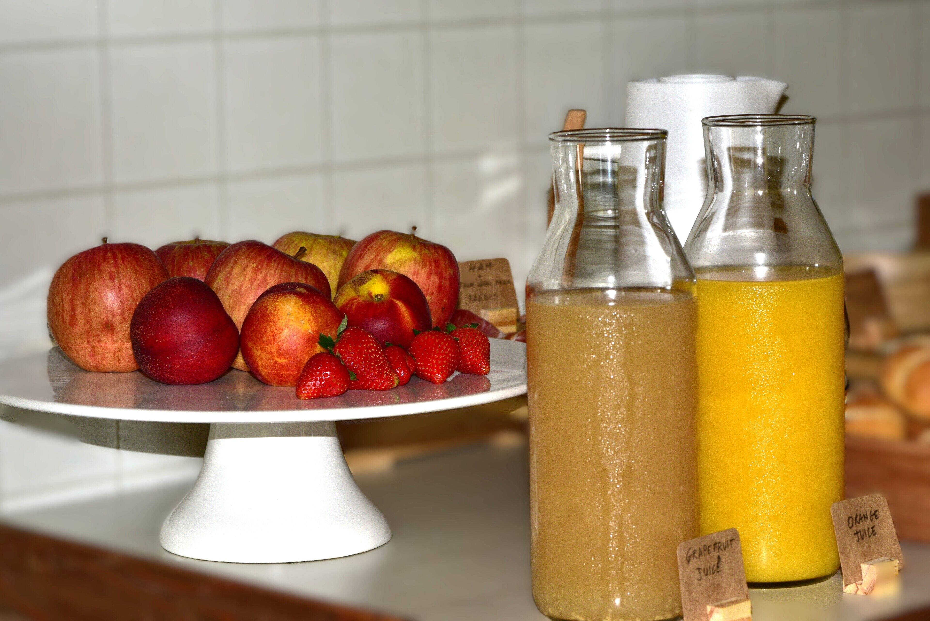 A fruit display with apples, strawberries, and two labeled bottles of juice.
