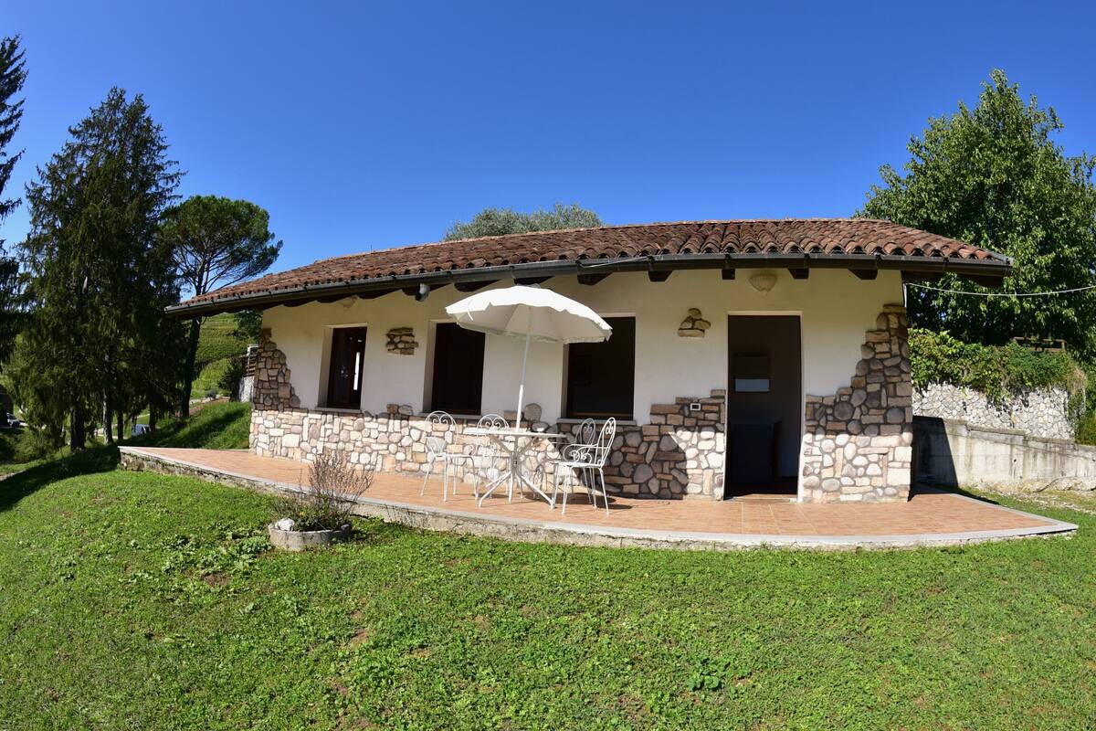 A house with a stone exterior, a tiled roof, and a patio with outdoor furniture.