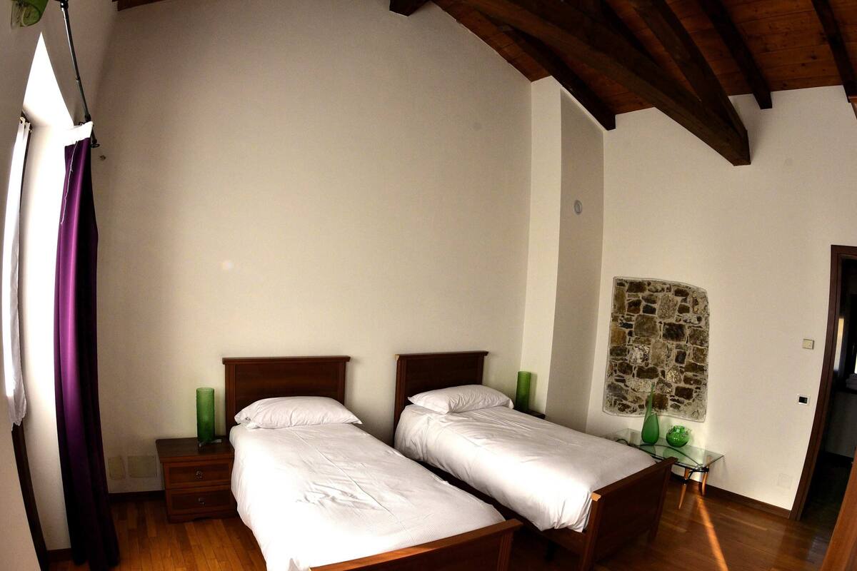 A room with two wooden beds, a stone wall, and a wooden ceiling.