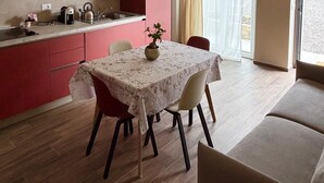 A compact kitchen with a dining area, a hanging light fixture, and a view through a window. - B&B NessunConfine CasaLaura with a magnificent view of the Oltrepò vineyards (Torricella Verzate)