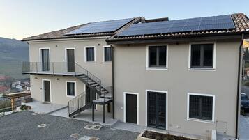 Ein zweistöckiges Gebäude mit einem Balkon, einer Treppe und Solaranlagen auf dem Dach.