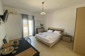 Une chambre propre et bien éclairée, avec un lit, des tables de chevet, un bureau avec une chaise et un téléviseur fixé au mur.