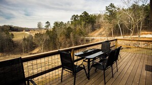 Une terrasse en bois avec une table et des chaises, donnant sur un paysage boisé.