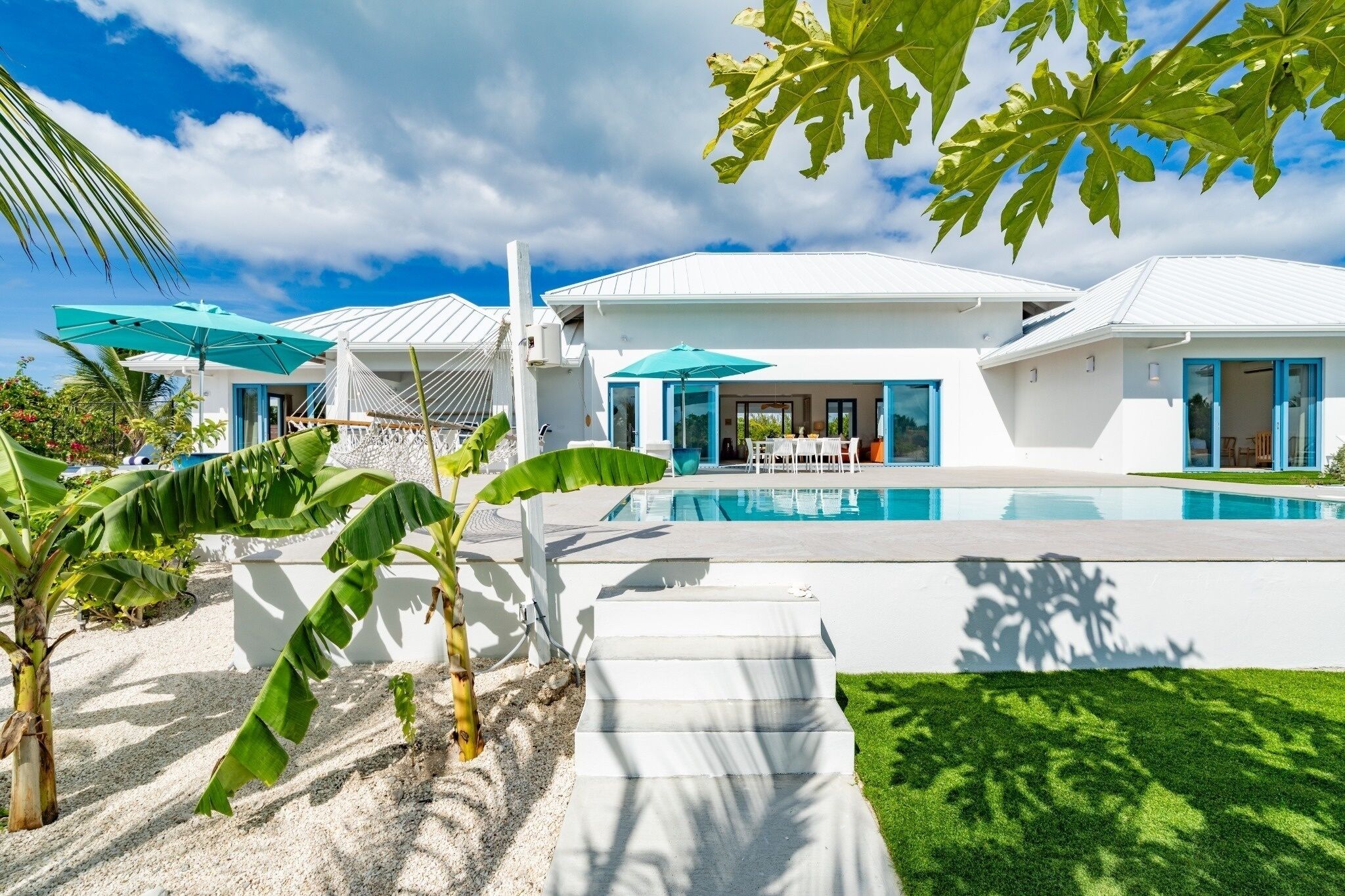 A modern house with a swimming pool, white exterior, and blue accents.