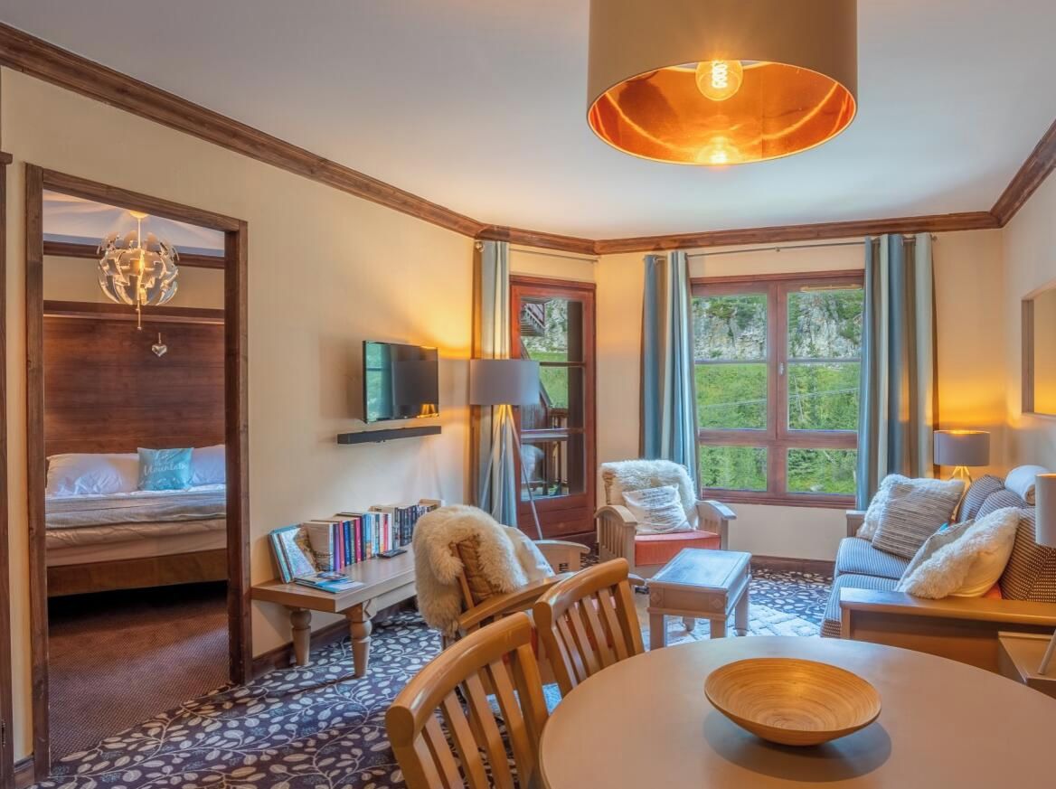 Ein gemütliches Zimmer mit einem Bett, einem Holztisch, einer Couch und einem Fernseher.