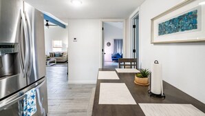A modern kitchen with a stainless steel refrigerator, a dining area with a table and chairs, and a living room with a sofa and a coffee table. - Cozy 2BR beach stay with a kitchenette—just a short walk to the sand. (Bolivar Peninsula)