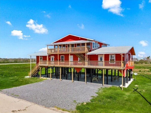 A two-story house with a red exterior, wooden deck, and a covered porch.