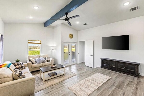 A spacious living room with a sofa, coffee table, and a flat-screen TV mounted on the wall. - Cozy 2BR beach stay with a kitchenette—just a short walk to the sand. (Bolivar Peninsula)