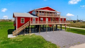 Een rode, twee verdiepingen tellende woning met een balkon, een trap en een grindpad.