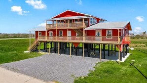Een huis met twee verdiepingen, een rode gevel, een balkon en een overdekte patio.