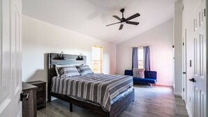 Een slaapkamer met een bed, een plafondventilator, een raam en een deur.