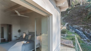 A bedroom with a bed, bedside table, and a large sliding glass door leading to a balcony with a view of a rocky landscape. - Villa Eugenia -Pool e Garden Retreat in Como lake (Blevio)