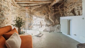 A rustic stone interior with a modern orange sofa, a small table with a candle, and a radiator. - Villa Eugenia -Pool e Garden Retreat in Como lake (Blevio)