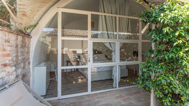 Una habitación acogedora con un ventanal grande, una cama y una pequeña mesa.