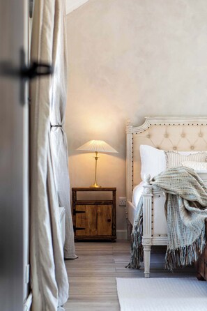 Une chambre à coucher avec un lit, une table de chevet, une lampe et un rideau.
