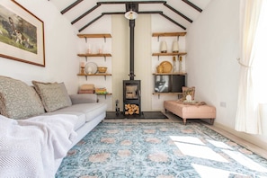 Un salon chaleureux avec un canapé, un tapis à motifs, des étagères en bois et une cheminée.