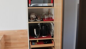 Una cocina equipada con microondas, cafetera y tetera.