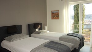 A hotel room with two beds, a large window, and a view of the city.