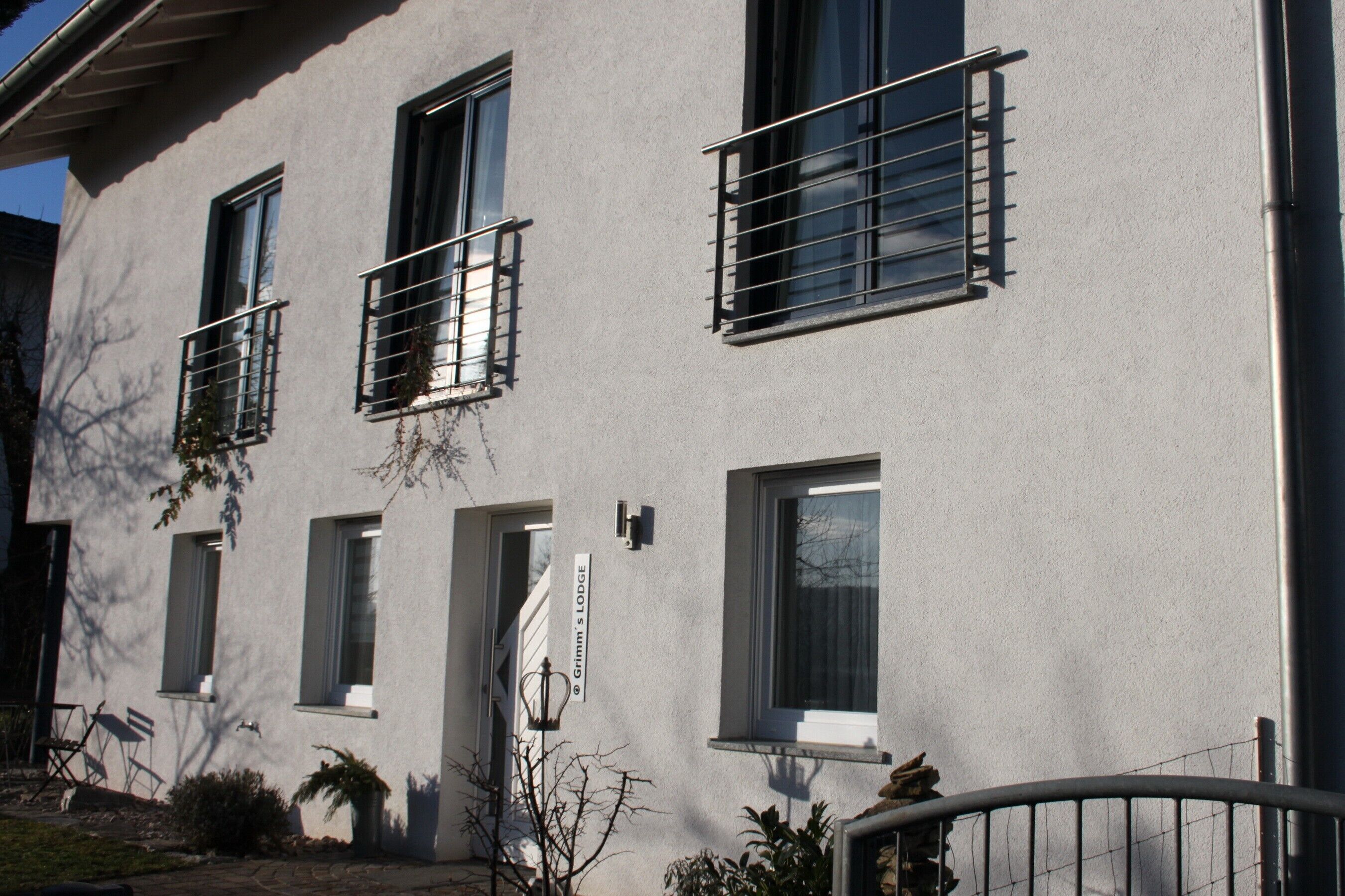 A building with multiple windows, some with metal bars, and a sign reading "Grimm's Lodge".
