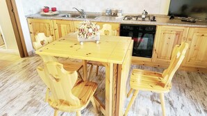 A wooden kitchen with a dining table and chairs, a sink, stove, and a dishwasher.