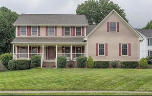 A two-story house with a front porch, a separate garage, and a well-maintained lawn. - FIFA World Cup Hub: 8 Mins to Arrowhead + Pool! (Independence)