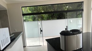 A modern kitchen with a built-in microwave, a large island, and a sliding glass door leading to a balcony. - Pousada Vila Palmital (Paraty)