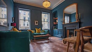 Ein Wohnzimmer mit einem grünen Sofa, einem Holztisch und einem Kamin.