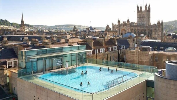 Ein Dachpool mit Glasreling, mit Blick auf eine historische Altstadt und markante Architektur.