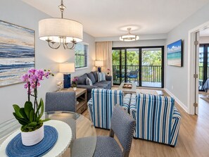 Ein modernes Wohnzimmer mit einer Sofagarnitur, einem Esstisch mit Stühlen und einem großen Fenster mit Blick auf Grünflächen.