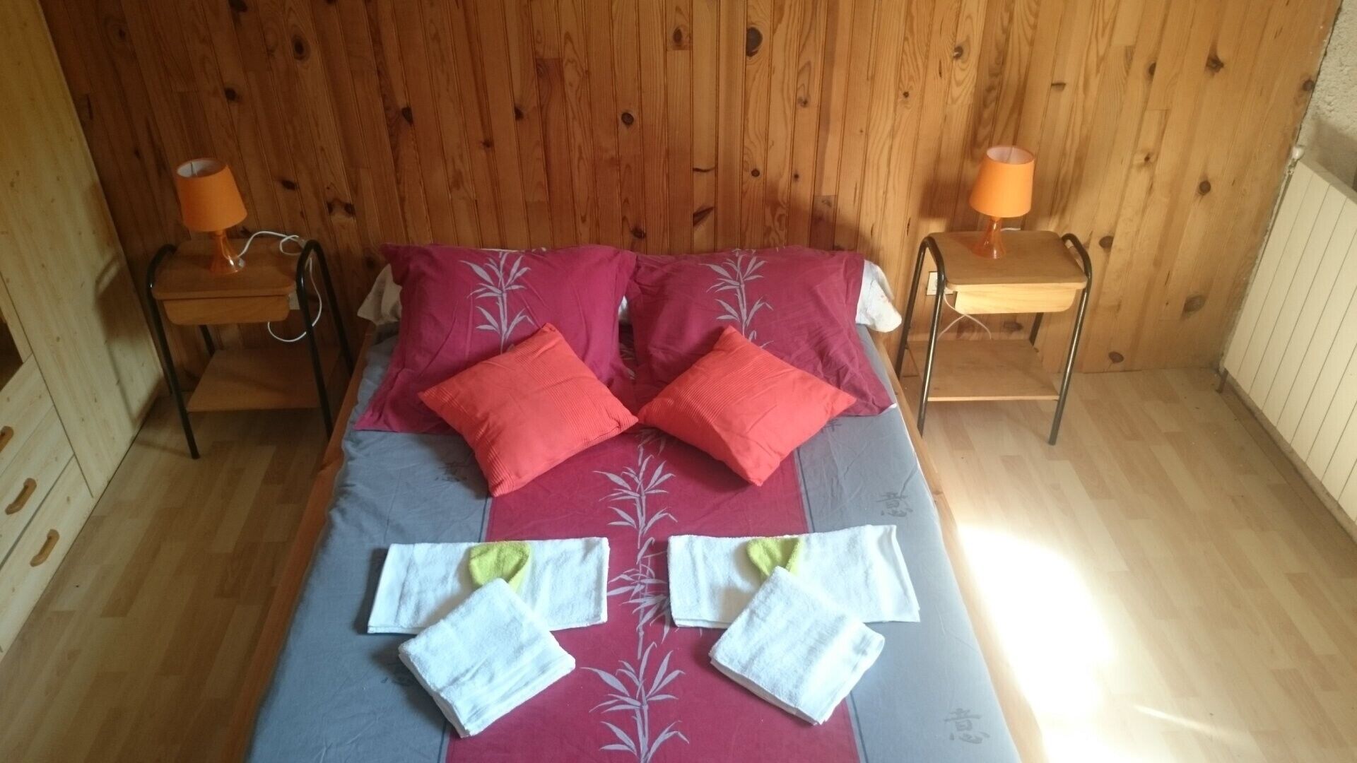 A wooden-paneled room with a bed, two nightstands, and two lamps.