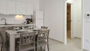 Una cocina moderna con armarios blancos, una mesa de comedor dispuesta con platos y vasos, y un equipo de aire acondicionado instalado en la pared.