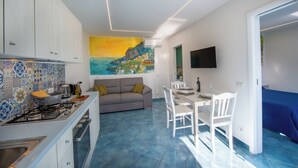 Een moderne keuken met een gasfornuis, een eethoek met een tafel en stoelen, een bank en een groot schilderij aan de muur.